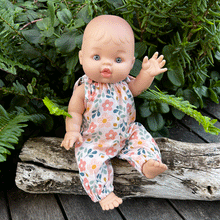 Baby doll in spring floral romper sitting in a garden 