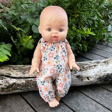 Baby doll in spring floral romper standing in a garden 
