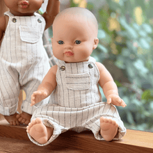 Baby doll wearing a striped romper with a blurred green outdoor background