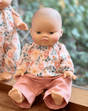 Baby doll wearing a floral top and pink pants.