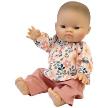 Baby doll wearing a floral shirt and pink pants on a white background
