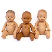 Three dolls of different skin tones sitting together on a white background
